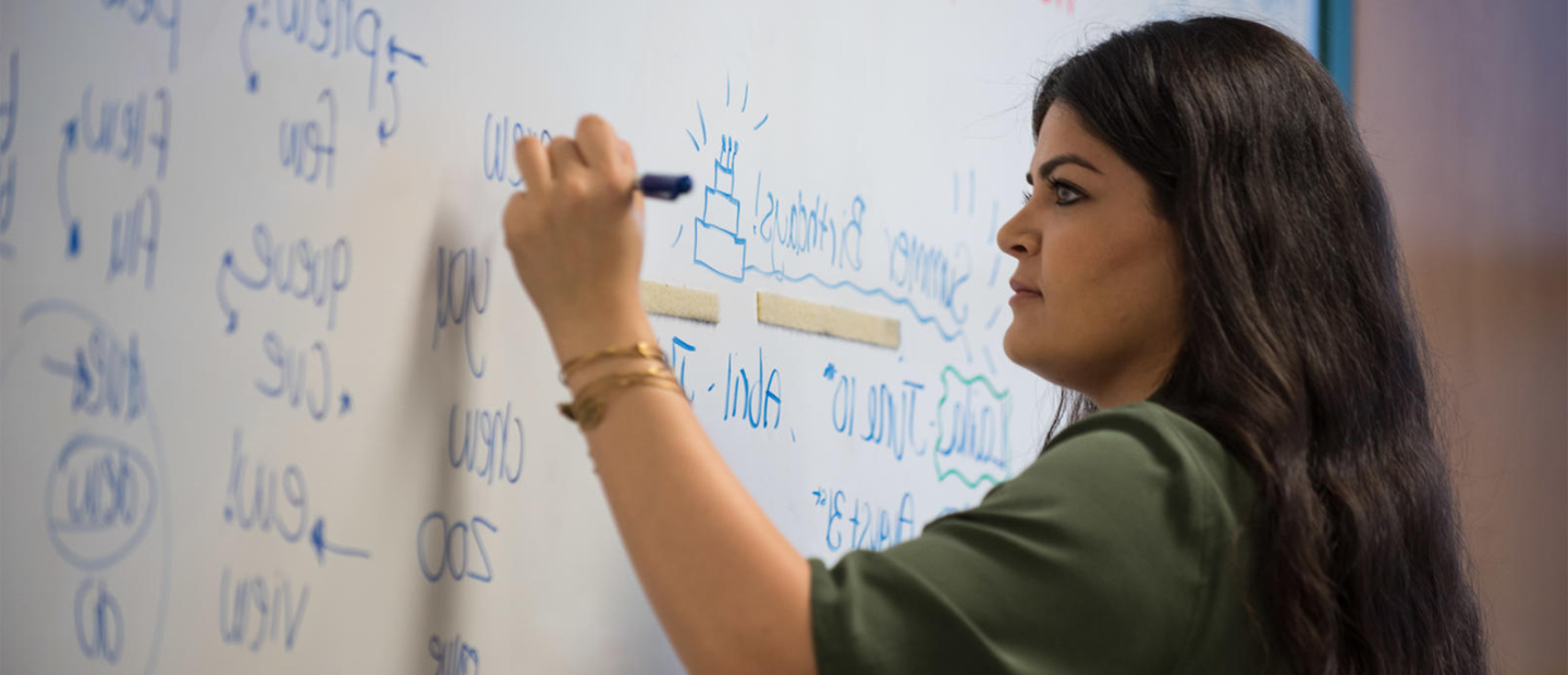 一个女人用蓝色记号笔在白板上写字.